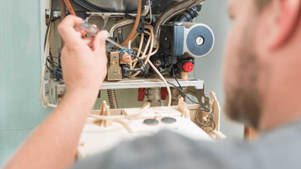 Technician adjusting internal furnace components with a screwdriver