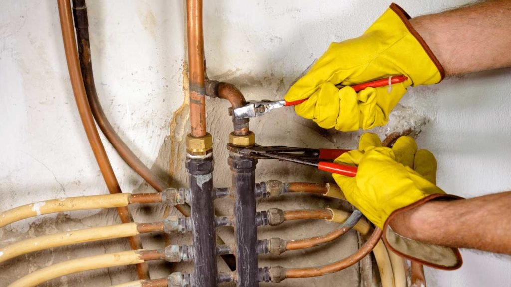 Technician repairing copper pipe fittings on a home heating system